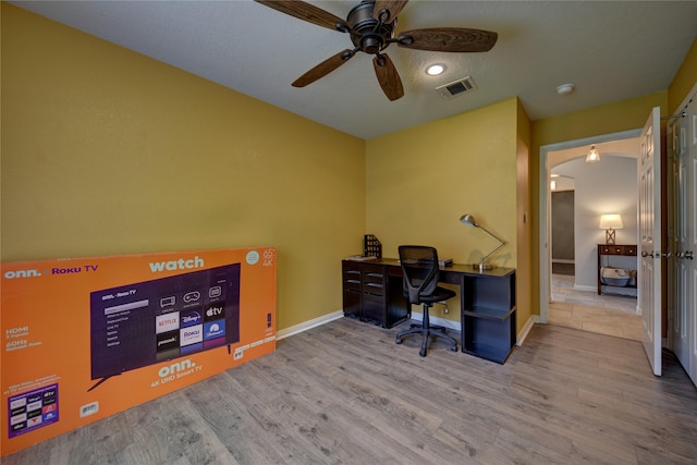 office space with visible vents, wood finished floors, baseboards, arched walkways, and a ceiling fan
