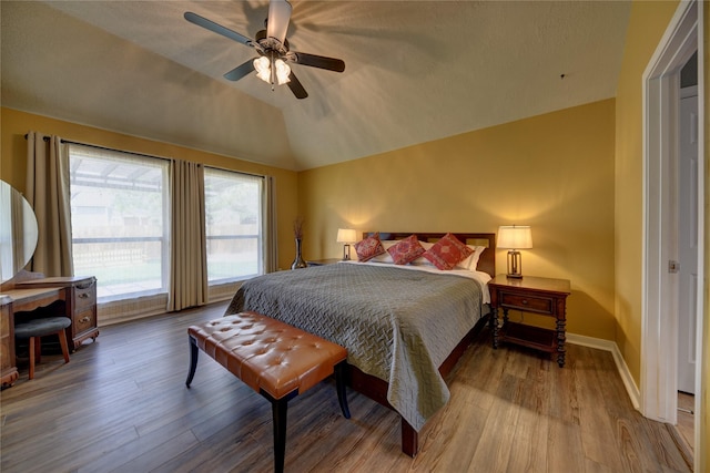 bedroom featuring baseboards, lofted ceiling, wood finished floors, and ceiling fan
