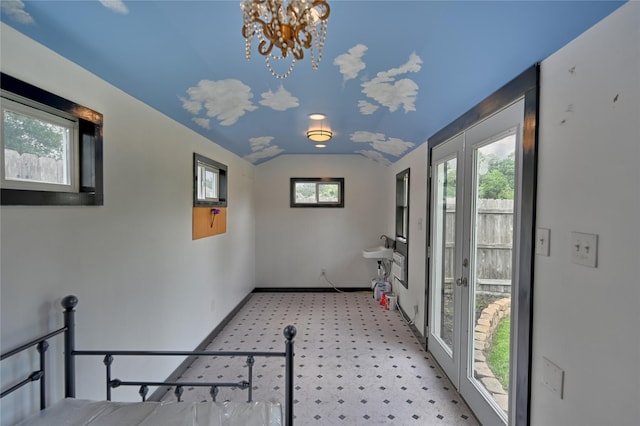 interior space featuring baseboards, a chandelier, and lofted ceiling
