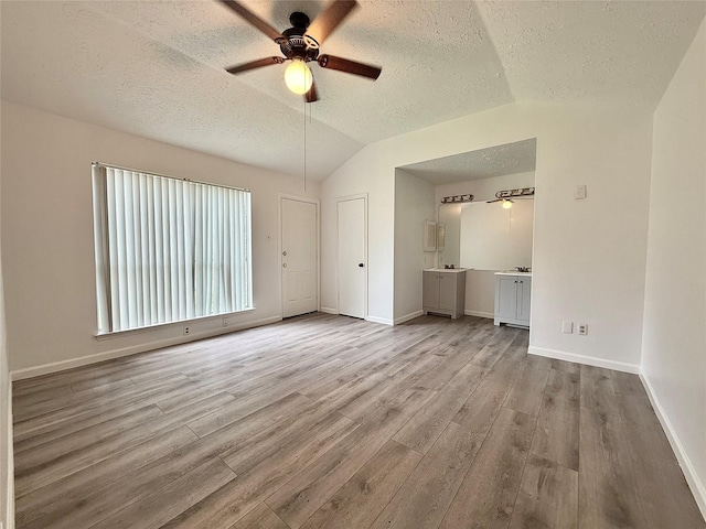 6410 Rancho Blanco Ct, Houston, TX 77083 - unfurnished living room with wood finished floors, a textured ceiling, a ceiling fan, vaulted ceiling, and baseboards