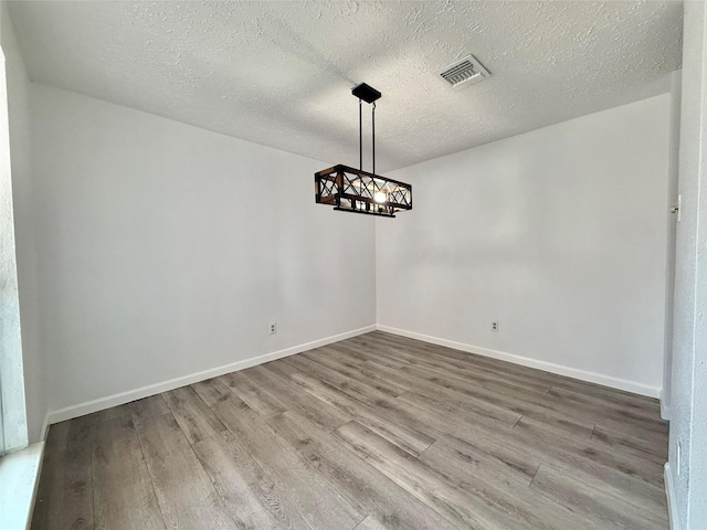 6410 Rancho Blanco Ct, Houston, TX 77083 - unfurnished dining area with wood finished floors, a chandelier, a textured ceiling, and baseboards