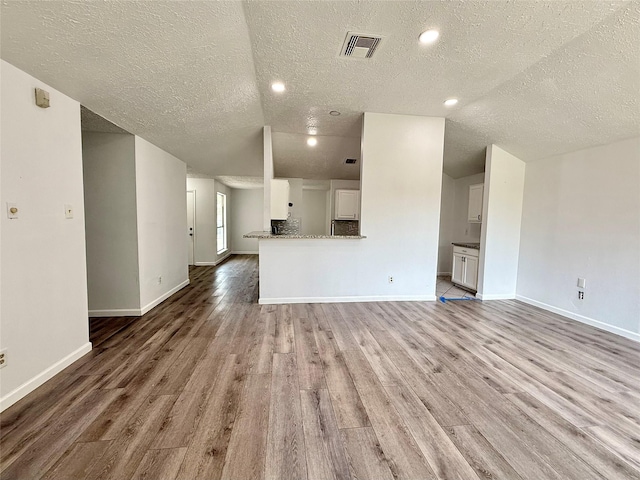 6410 Rancho Blanco Ct, Houston, TX 77083 - unfurnished living room with a textured ceiling, light wood-style flooring, baseboards, and recessed lighting