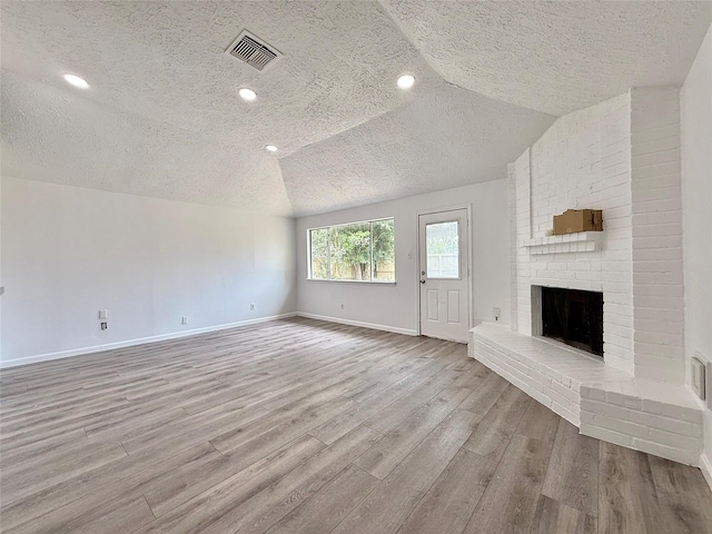 6410 Rancho Blanco Ct, Houston, TX 77083 - unfurnished living room with a textured ceiling, wood finished floors, baseboards, a brick fireplace, and lofted ceiling