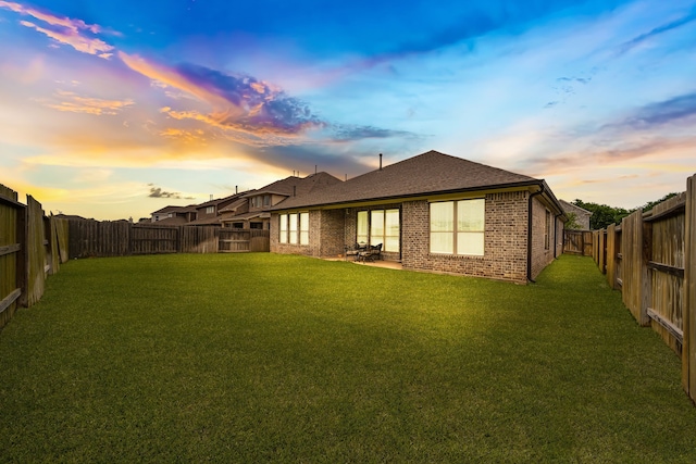 32927 Franklin Brooks Dr, Brookshire, TX 77423 - back of property at dusk with a yard, brick siding, a shingled roof, and a fenced backyard