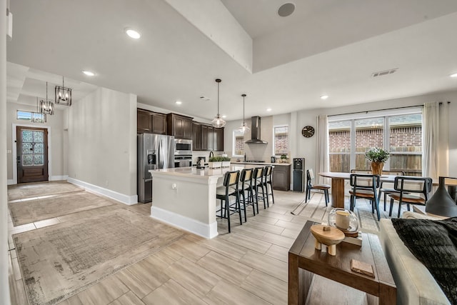 32927 Franklin Brooks Dr, Brookshire, TX 77423 - kitchen featuring dark brown cabinets, wall chimney range hood, a kitchen bar, light countertops, and stainless steel appliances