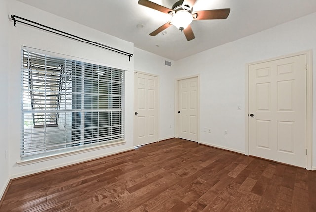 unfurnished bedroom with baseboards, ceiling fan, wood finished floors, and visible vents