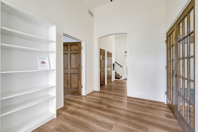 hallway with visible vents, arched walkways, baseboards, and wood finished floors