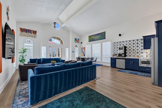 living area with baseboards, high vaulted ceiling, and light wood-style flooring