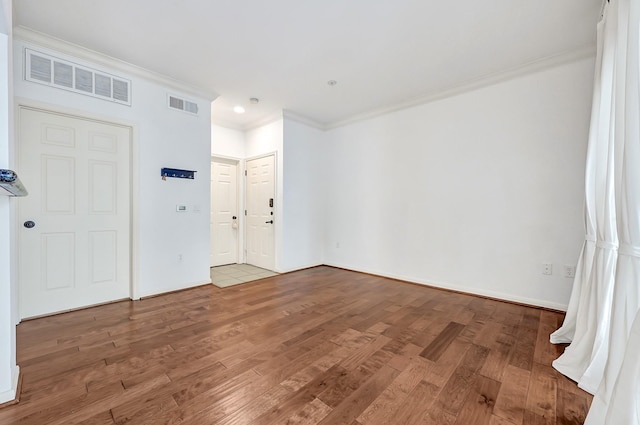 empty room featuring visible vents, crown molding, and wood finished floors