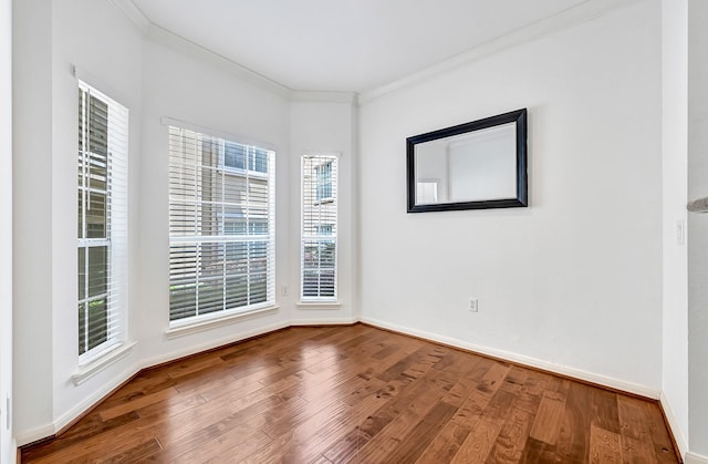 spare room with baseboards, ornamental molding, and wood finished floors