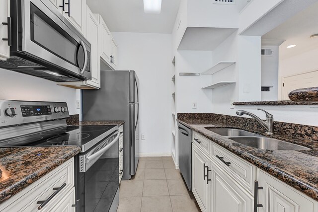 kitchen with open shelves, a sink, dark stone countertops, stainless steel appliances, and white cabinetry