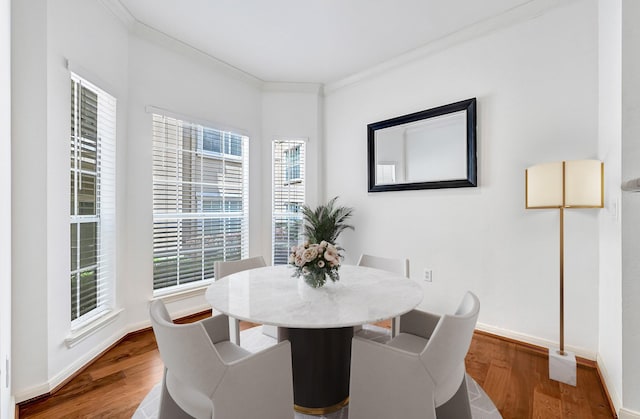 dining room with baseboards, ornamental molding, and wood finished floors