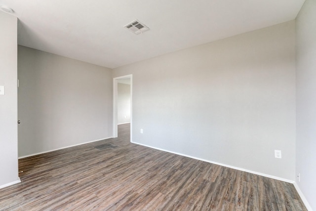 unfurnished room featuring baseboards, visible vents, and dark wood-style floors