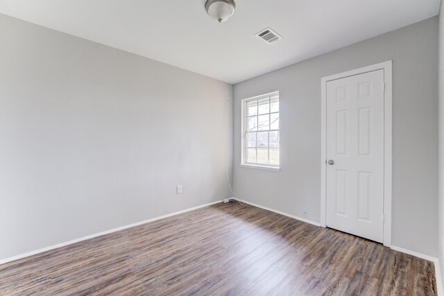 unfurnished room featuring baseboards, wood finished floors, and visible vents