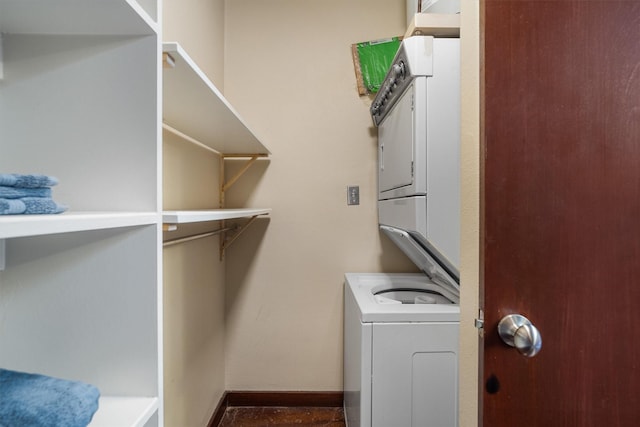 clothes washing area with baseboards, laundry area, and stacked washer / dryer
