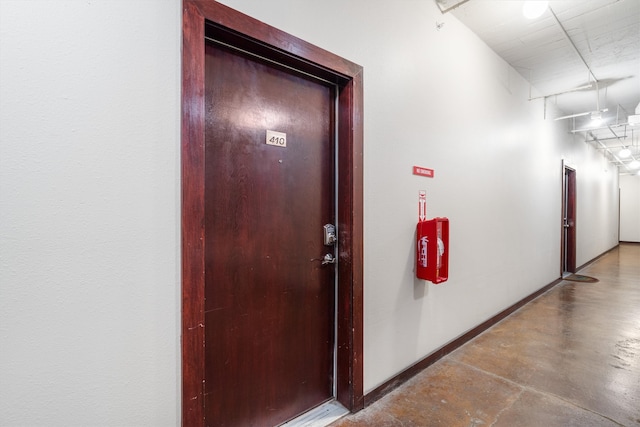 hall with finished concrete floors and baseboards