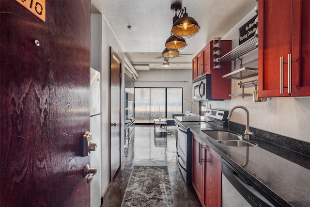 kitchen featuring dark brown cabinets, dark countertops, ceiling fan, a sink, and stainless steel appliances