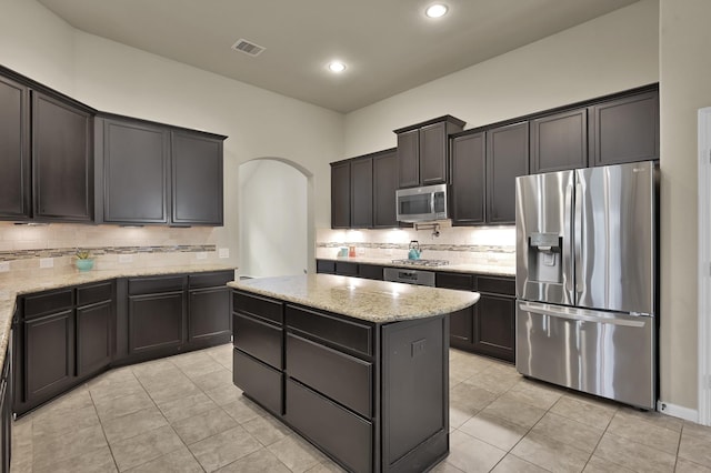 7610 Willow School Dr, Spring, TX 77389 - kitchen featuring decorative backsplash, a kitchen island, visible vents, arched walkways, and stainless steel appliances