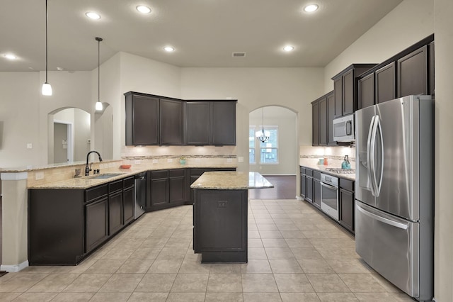 7610 Willow School Dr, Spring, TX 77389 - kitchen with decorative backsplash, arched walkways, light stone counters, a sink, and appliances with stainless steel finishes