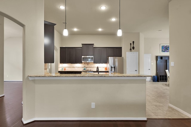 7610 Willow School Dr, Spring, TX 77389 - kitchen featuring appliances with stainless steel finishes, hanging light fixtures, light stone countertops, arched walkways, and baseboards