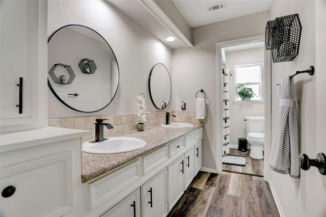 bathroom featuring toilet, visible vents, a sink, and wood finished floors