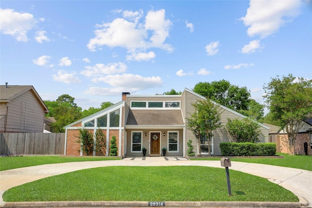 mid-century inspired home with brick siding, a front lawn, fence, and a chimney