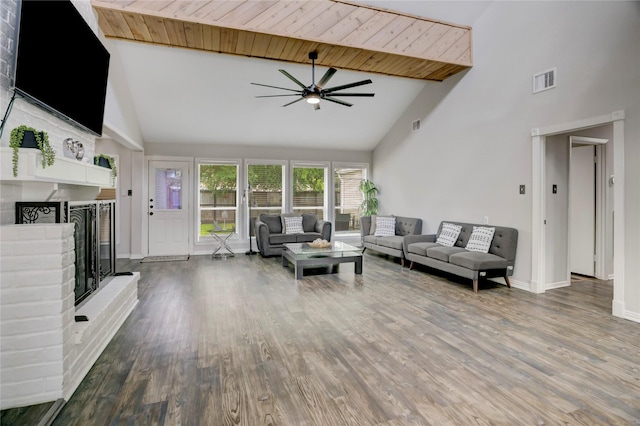 living room featuring ceiling fan, visible vents, a fireplace, wood finished floors, and high vaulted ceiling