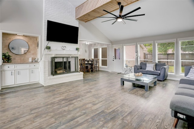 living area featuring a fireplace, high vaulted ceiling, ceiling fan, and wood finished floors