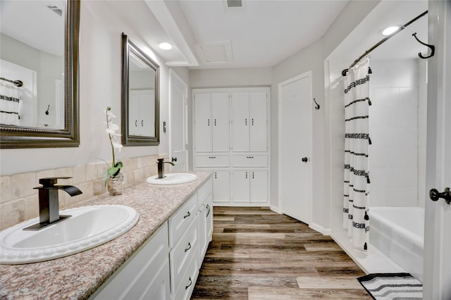 full bath with double vanity, a sink, shower / tub combo, and wood finished floors
