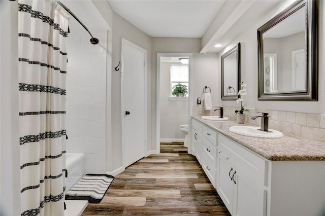 bathroom featuring double vanity, a sink, wood finished floors, and shower / bath combo