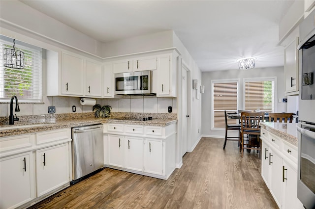 kitchen featuring stainless steel appliances, a notable chandelier, a sink, and wood finished floors