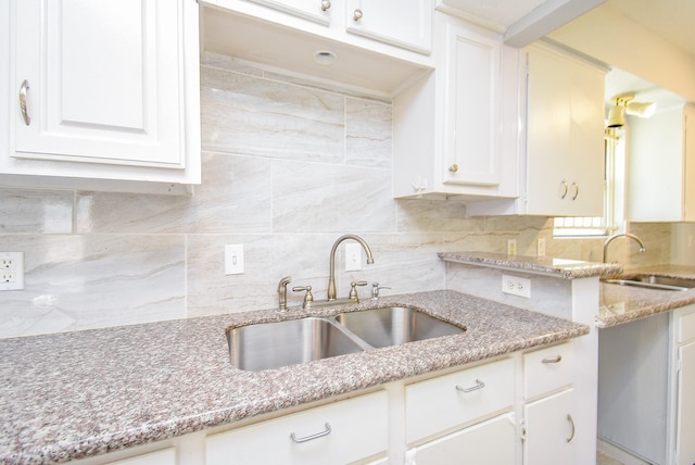 kitchen featuring light stone counters, tasteful backsplash, and a sink