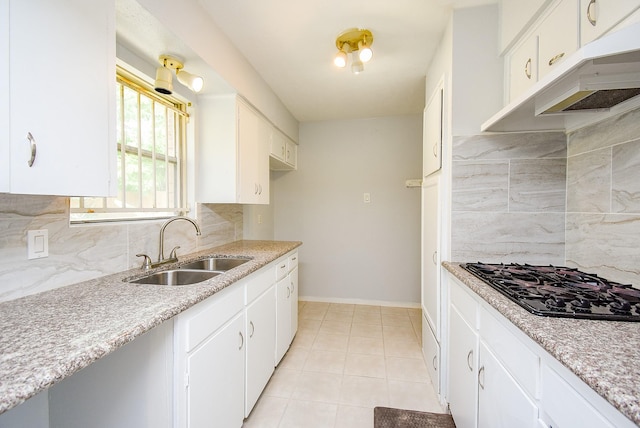 kitchen with light tile patterned floors, a sink, black gas cooktop, backsplash, and under cabinet range hood
