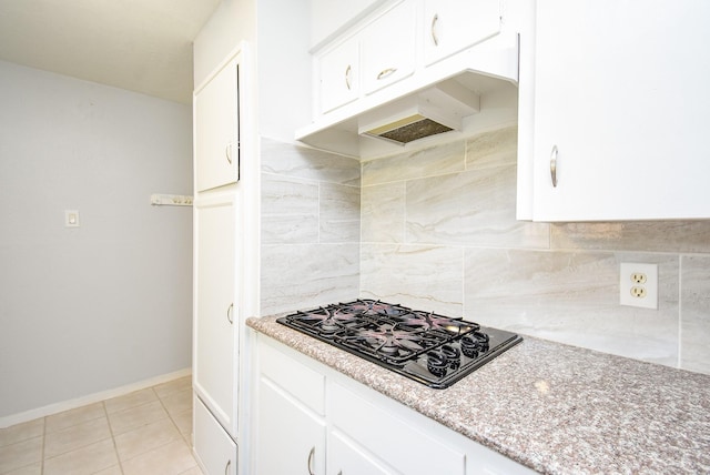 kitchen featuring white cabinetry, black gas cooktop, backsplash, light stone counters, and light tile patterned flooring
