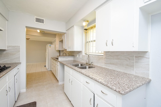 kitchen with light tile patterned floors, a sink, freestanding refrigerator, visible vents, and tasteful backsplash
