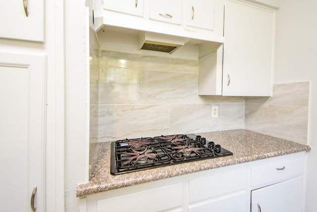 kitchen featuring white cabinets, black gas cooktop, under cabinet range hood, and tasteful backsplash