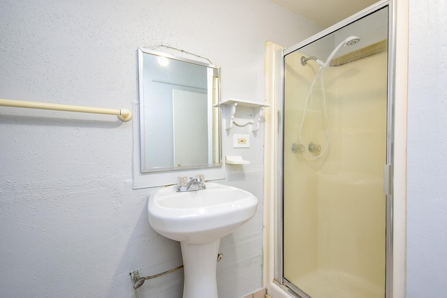 bathroom with a stall shower and a sink