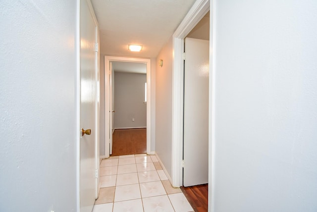 corridor featuring baseboards and light tile patterned flooring