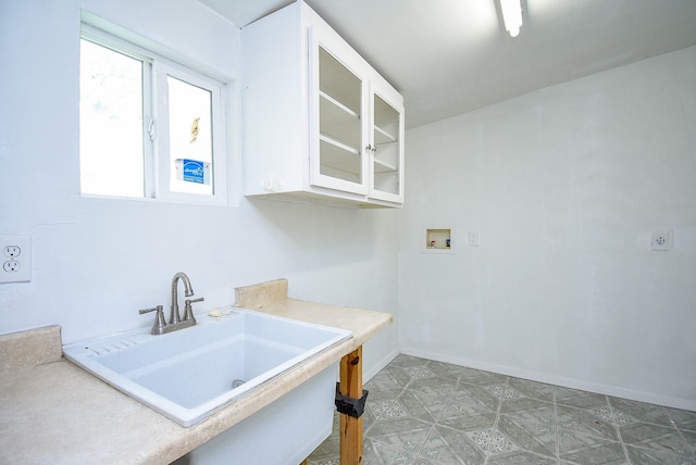 laundry room featuring laundry area, baseboards, washer hookup, and a sink