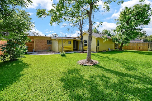 rear view of house featuring a lawn and fence