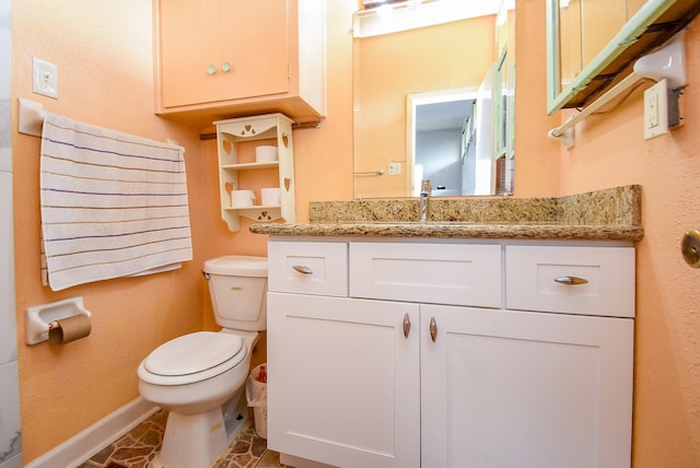 half bathroom featuring toilet, baseboards, and vanity