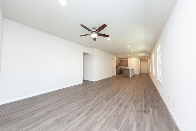 unfurnished living room featuring a ceiling fan, baseboards, recessed lighting, and light wood-style flooring