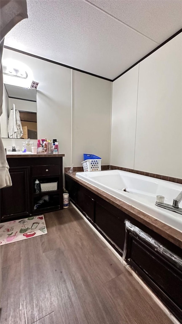 full bath with vanity, a bath, a textured ceiling, and wood finished floors