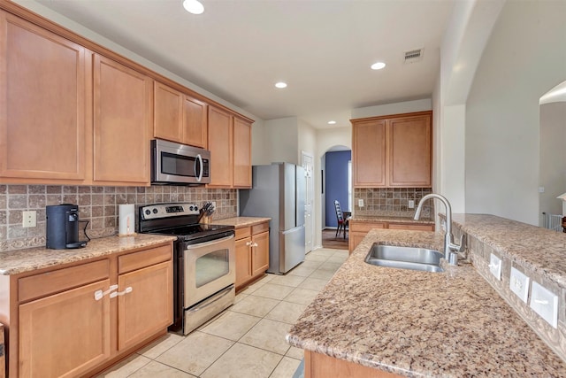 kitchen featuring visible vents, appliances with stainless steel finishes, arched walkways, a sink, and light tile patterned flooring