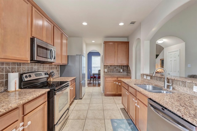kitchen with backsplash, visible vents, appliances with stainless steel finishes, arched walkways, and a sink