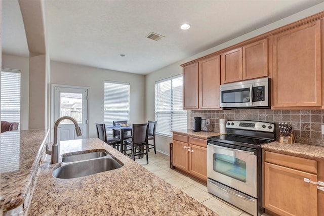 kitchen with visible vents, tasteful backsplash, a sink, light tile patterned floors, and stainless steel appliances