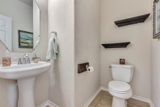 bathroom with baseboards, tile patterned flooring, and toilet