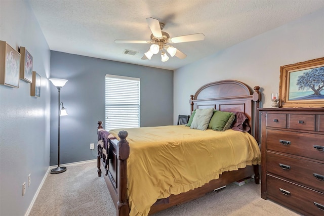 bedroom featuring visible vents, a textured ceiling, baseboards, and light colored carpet