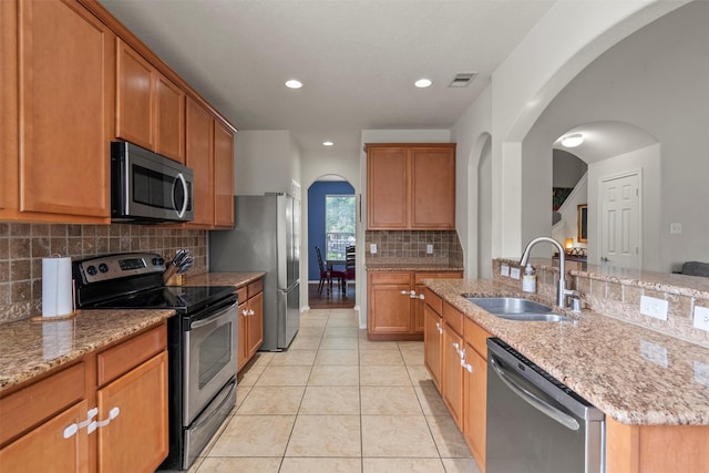 31611 Cape May Ct, Spring, TX 77386 - kitchen featuring stainless steel appliances, a sink, arched walkways, light stone counters, and recessed lighting
