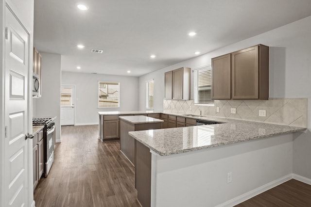 2340 Mooneye Ct, Conroe, TX 77384 - kitchen featuring stainless steel appliances, dark wood finished floors, visible vents, and a peninsula